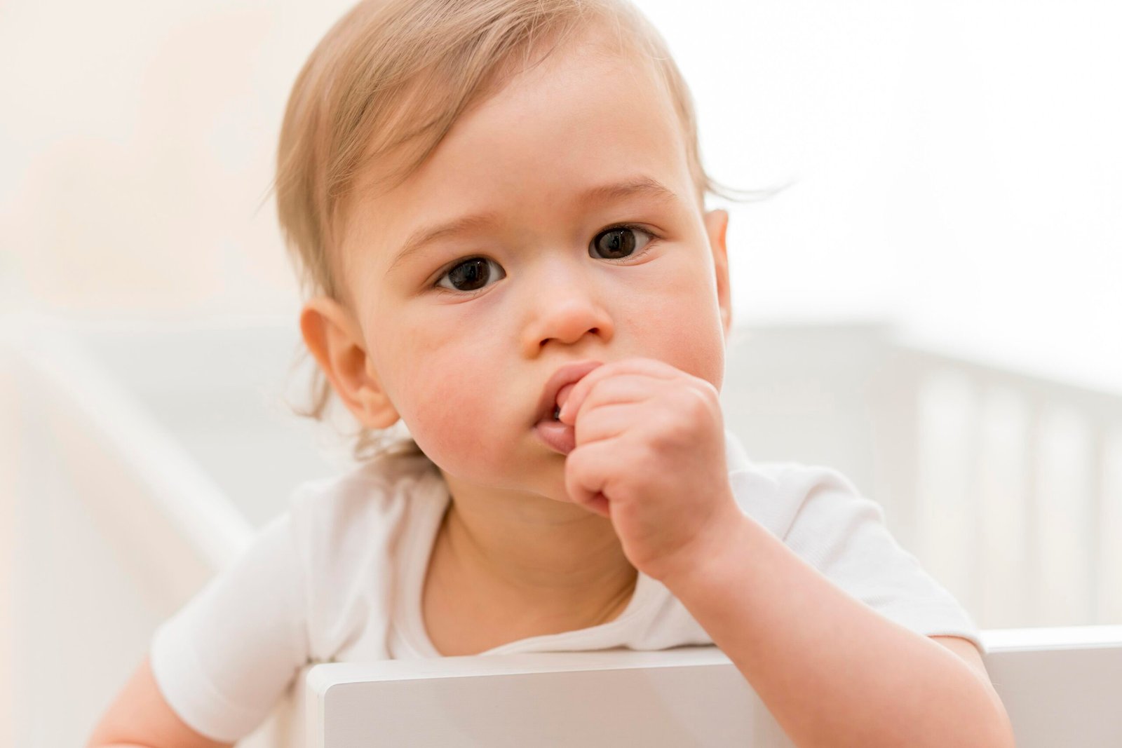 Baby chewing on a cold face washer for gum relief – teething baby sleep support
